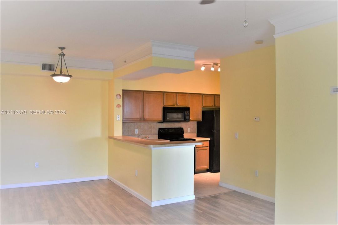 Kitchen featuring wood cabinetry, a breakfast bar, and integrated appliances, complemented by crown molding and wood-finish flooring