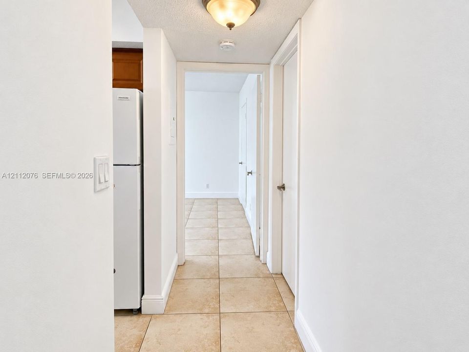 Hallway featuring tile flooring, smooth walls, and a dome-style flush-mount ceiling light fixture