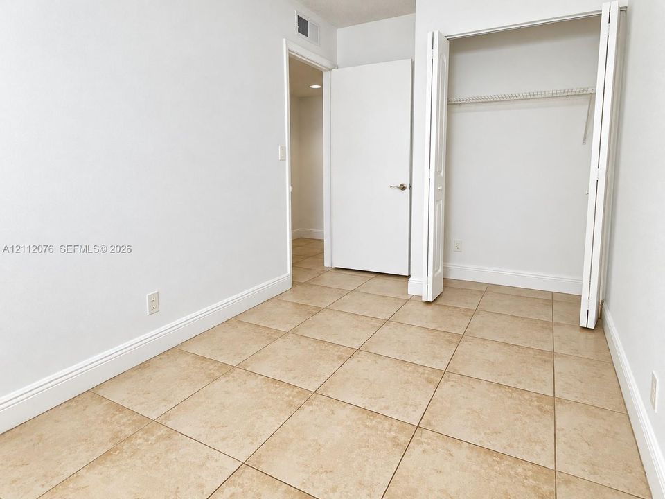 Neutral-toned square tile flooring, built-in closet with double bifold doors, and crisp white interior doors