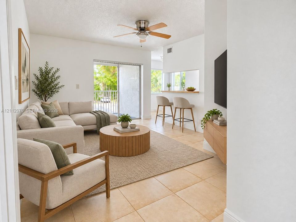 Open-concept interior featuring light-toned tile flooring, a built-in kitchen pass-through counter, a ceiling fan with light fixture, and a sliding glass door providing external access