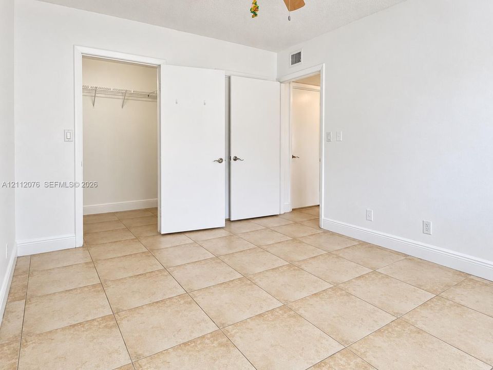 Interior space featuring large-format stone-finish floor tiling, neutral wall finishes, a walk-in closet, and white interior doors with brushed nickel hardware