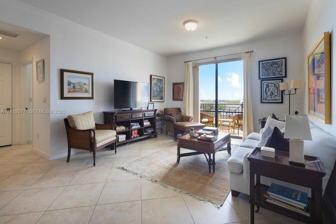 Living area featuring large-format ceramic tile flooring, sliding glass doors, and a private balcony