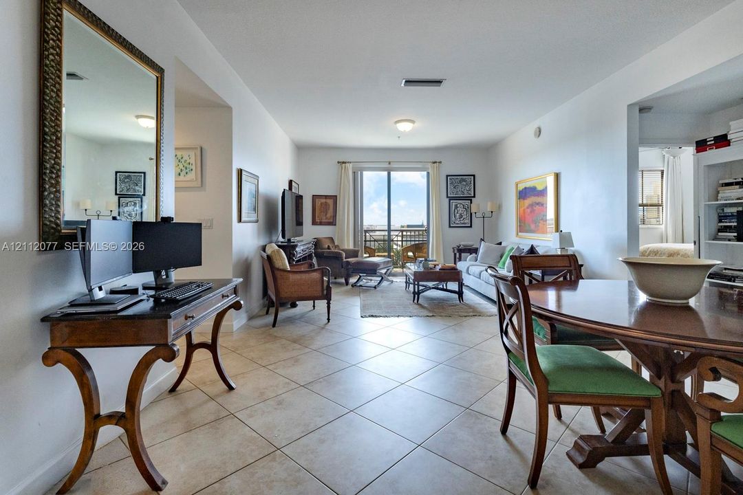 Open-concept living space featuring large-format ceramic tile flooring, neutral wall finishes, and sliding glass doors with access to an exterior balcony