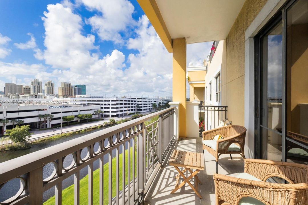 Covered balcony featuring metal railing with geometric circular accents, concrete flooring, and sliding glass door access