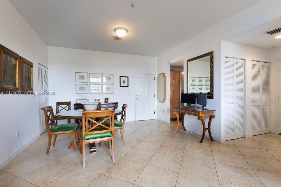 Open-concept floor plan featuring neutral stone-finish tile flooring, white interior walls, and dual-closet storage with louvered doors