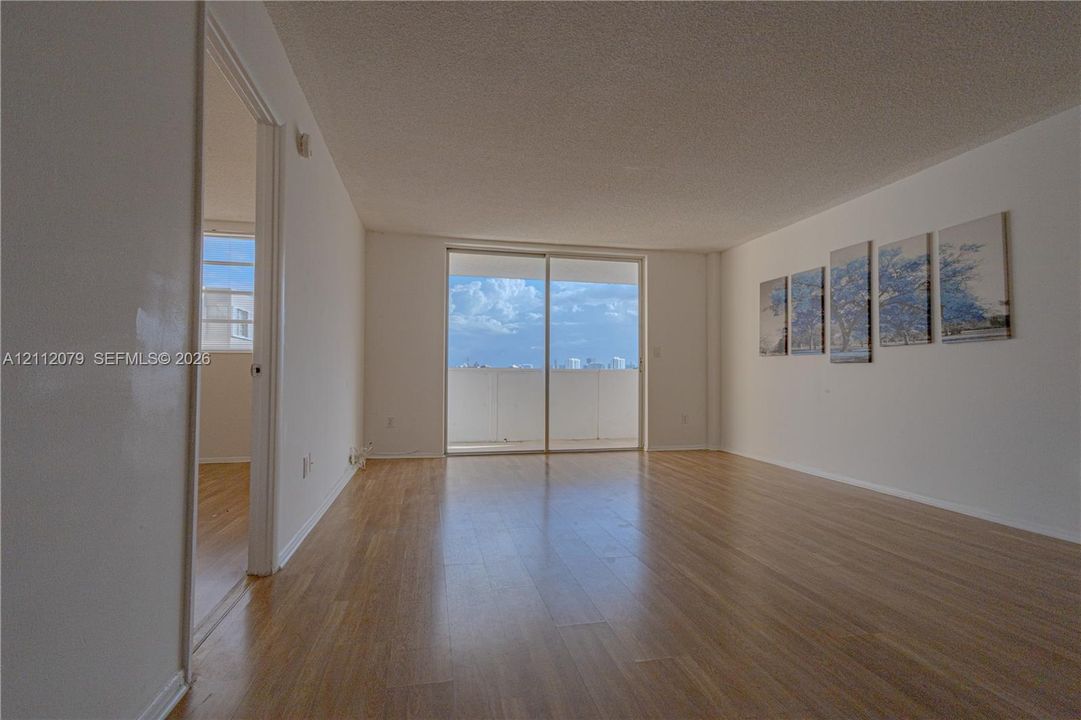 Living area featuring wood-finish flooring, sliding glass balcony doors, and a neutral color palette