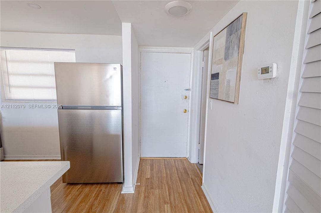 Stainless steel refrigerator, wood-finish flooring, solid-panel entry door, and recessed lighting