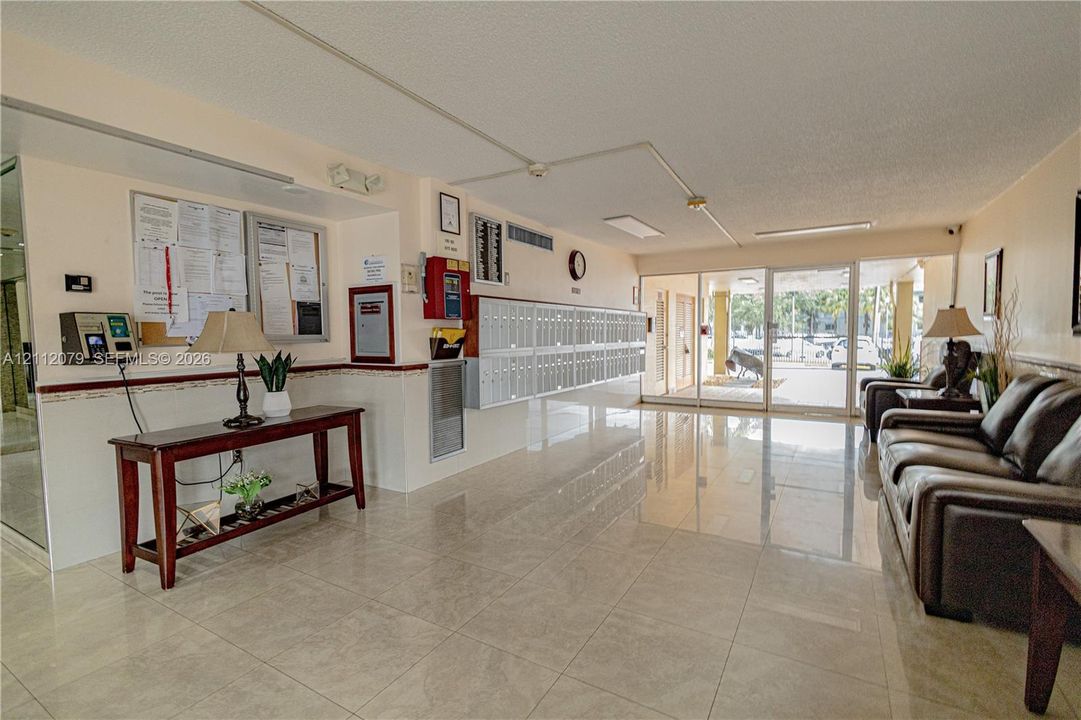 Lobby area featuring polished tile flooring, integrated wall-mounted mailboxes, glass-paned entrance doors, and recessed ceiling lighting
