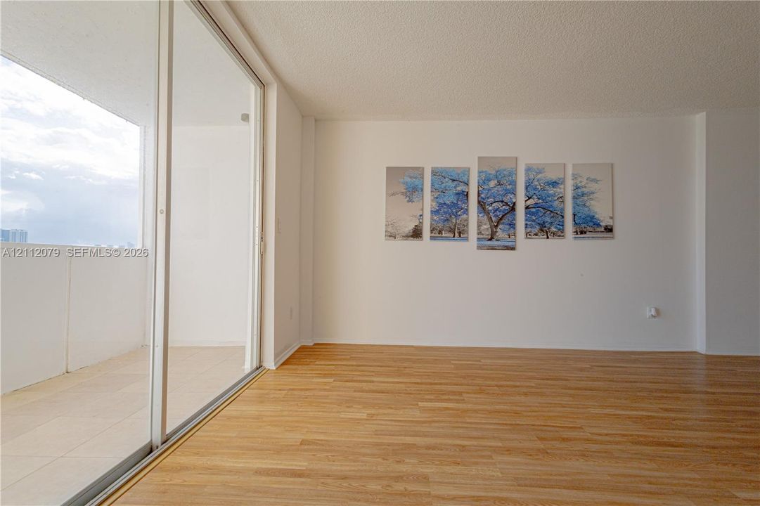Interior space featuring wood-finish flooring and expansive floor-to-ceiling glass sliding doors opening to a private balcony with tile surfacing