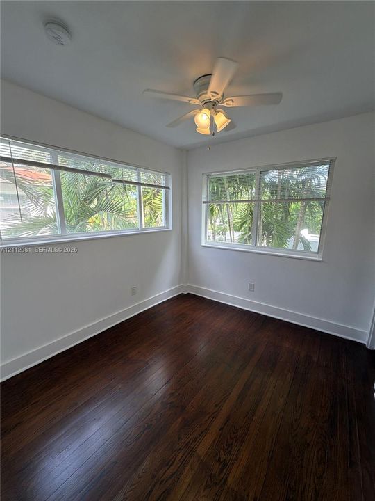 Room featuring wood-finish flooring, multi-pane windows, and a ceiling-mounted light fixture with a central fan