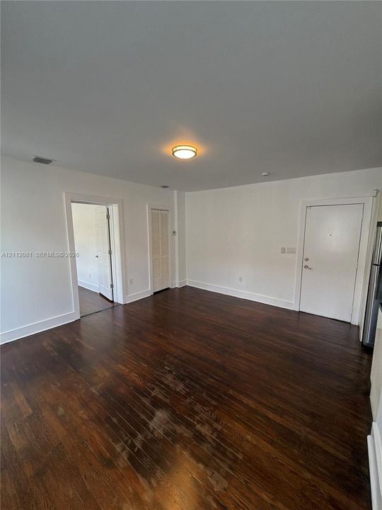 Interior space featuring wood-finish flooring, white walls, flush-mount ceiling lighting, and a bifold closet door
