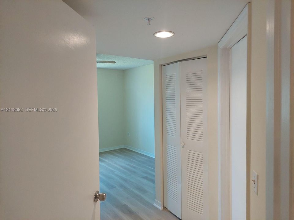 Hallway featuring wood-finish flooring, recessed lighting, and a white bifold louvered closet door