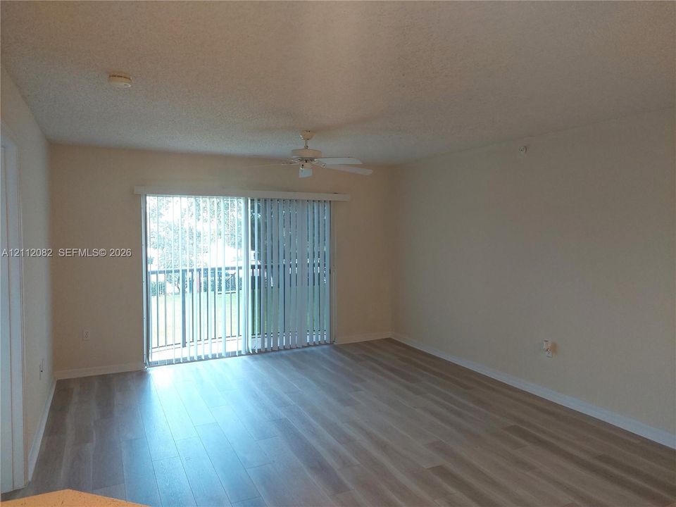 Neutral-toned interior featuring wood-finish flooring, a ceiling fan, and sliding glass doors providing access to the exterior
