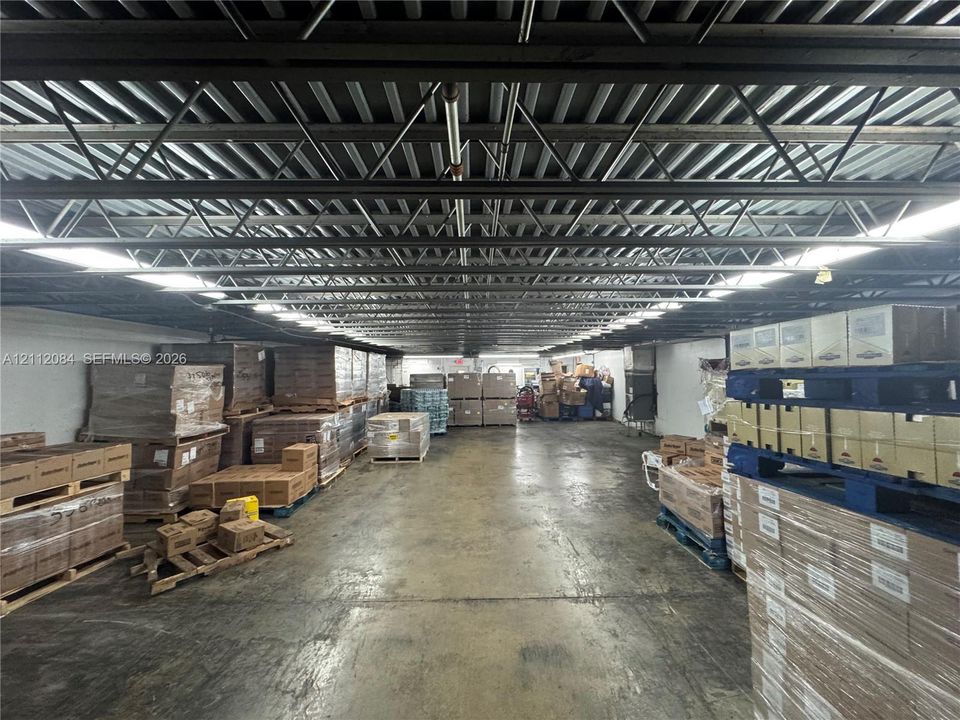 Industrial-style warehouse space featuring an open-span floor plan, exposed metal joist ceiling, polished concrete flooring, and linear recessed overhead lighting