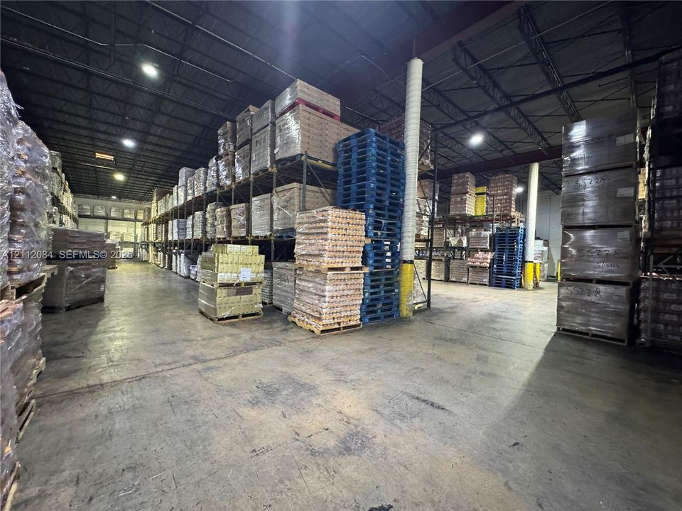 Industrial warehouse space featuring high-clearance exposed ceilings, concrete flooring, and multi-level heavy-duty pallet racking systems