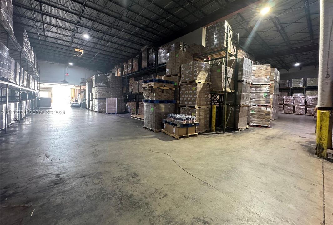 Industrial warehouse space featuring high-clearance ceilings with exposed structural steel, durable concrete flooring, and metal racking systems