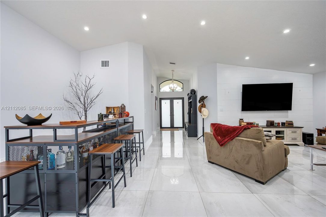 Large-format tile flooring, shiplap wall accent, recessed lighting, and double-entry doors with a transom window