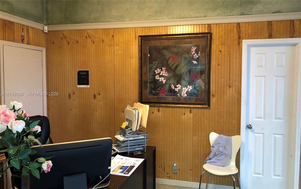 Interior space featuring vertical wood paneling, crown molding, and a six-panel door