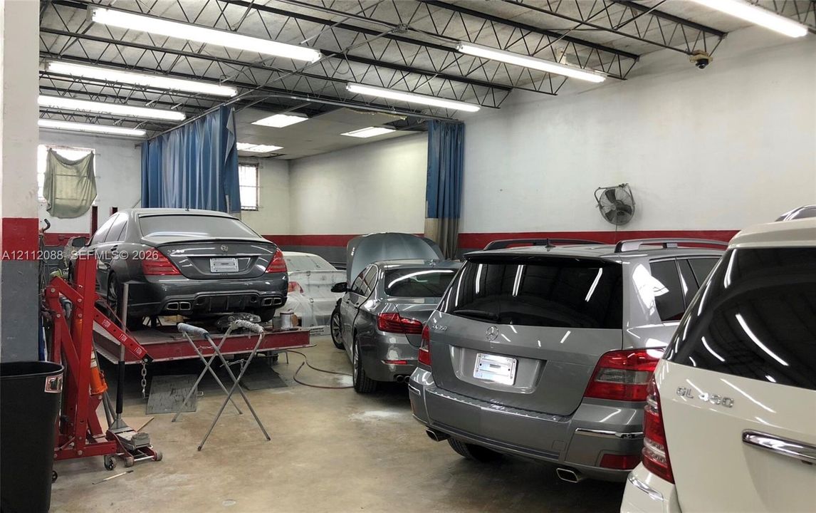 Spacious garage with high-clearance exposed joist ceiling, industrial LED lighting, concrete flooring, and retractable curtain partitions