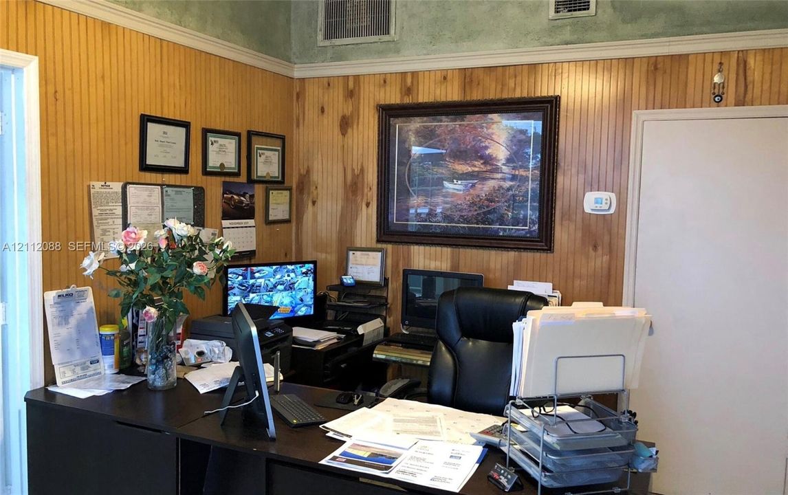 Interior room featuring vertical wood-plank wall paneling, crown molding, and a solid-core door