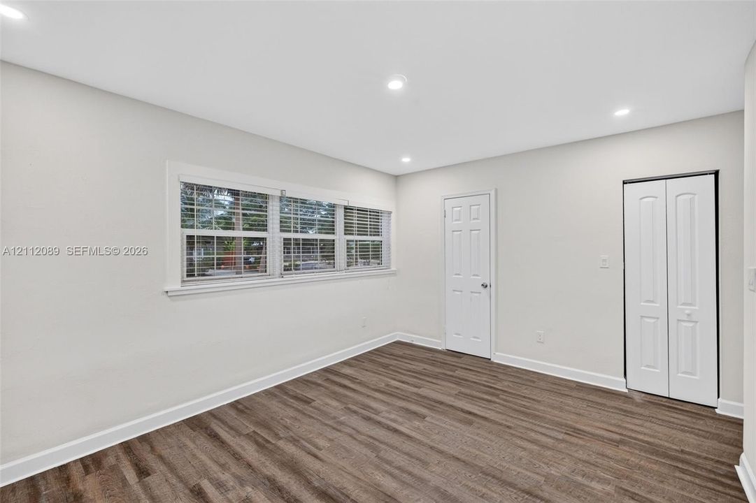 Room featuring wood-finish flooring, recessed lighting, multi-pane windows with blinds, and a white six-panel closet door