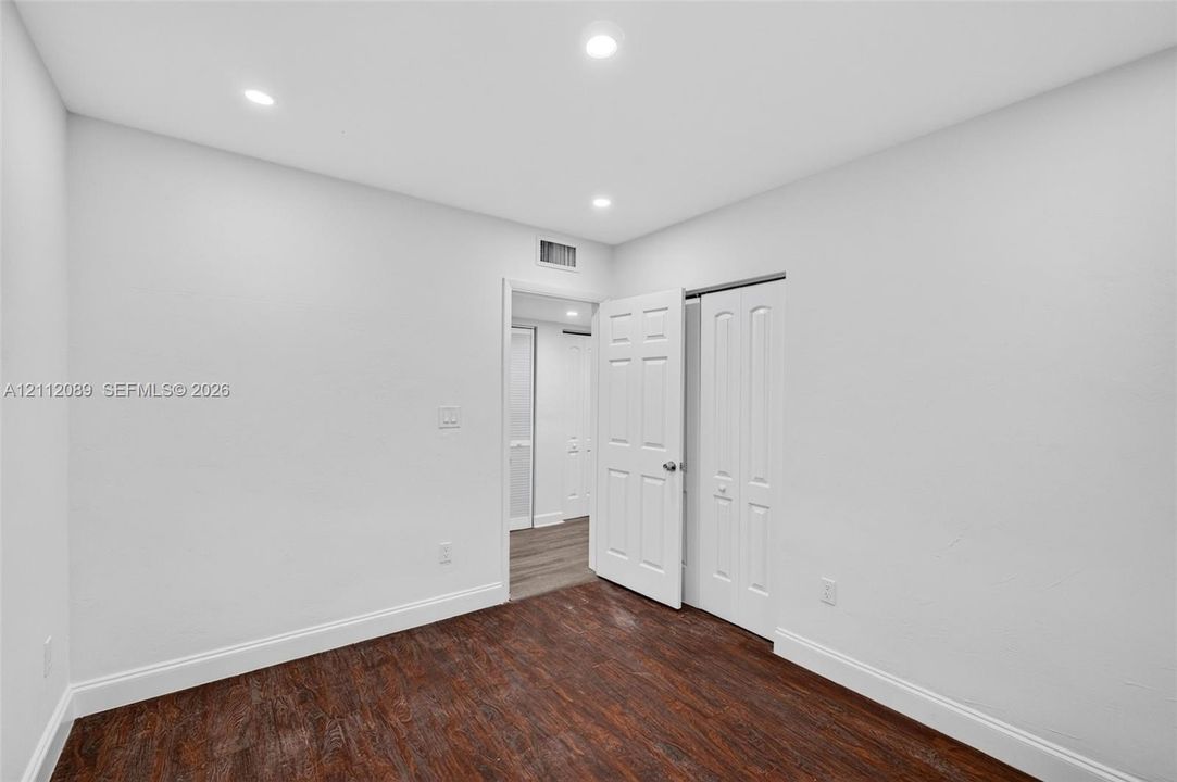 Interior space featuring dark wood-finish flooring, recessed lighting, and white paneled doors