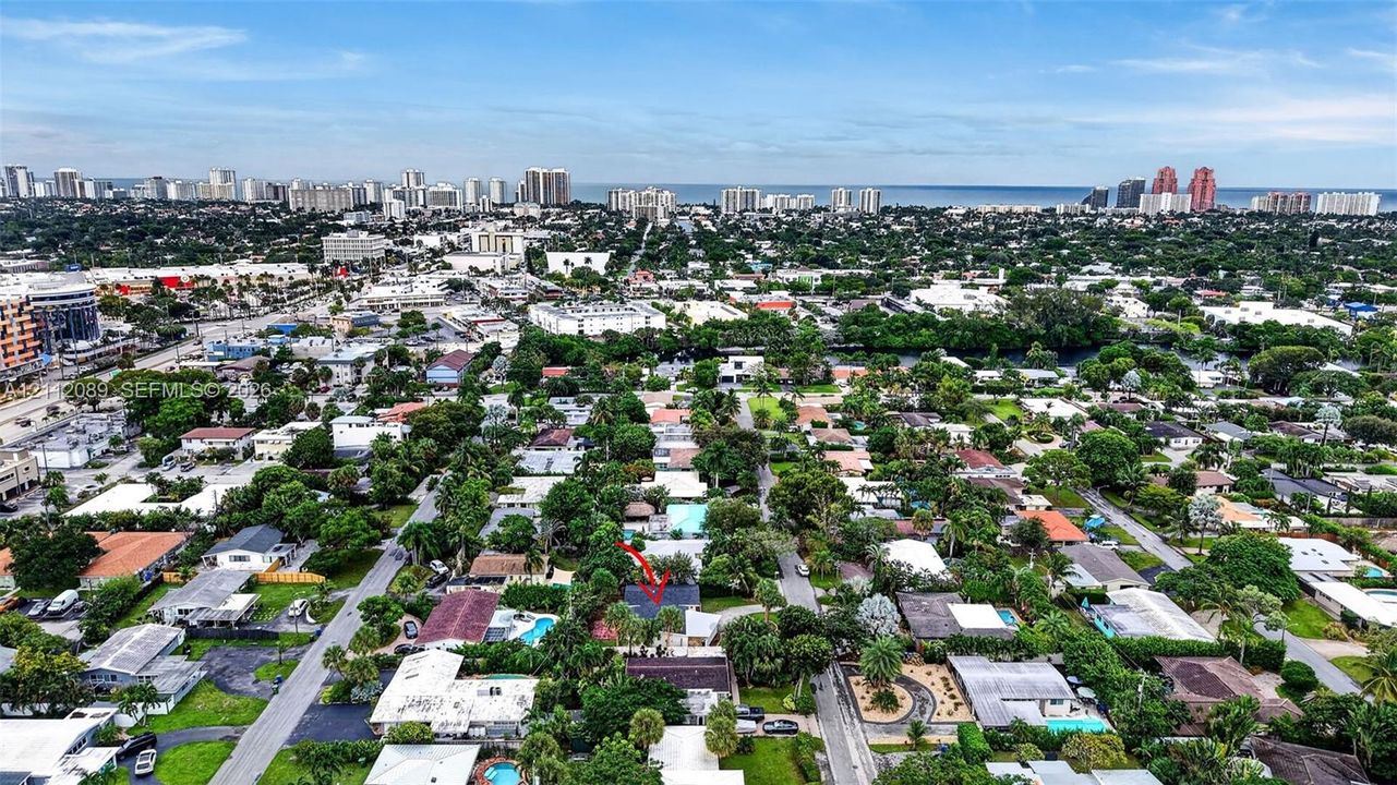 Aerial perspective of the property featuring mature landscaping and a roofline designated by marker, situated within a coastal urban environment