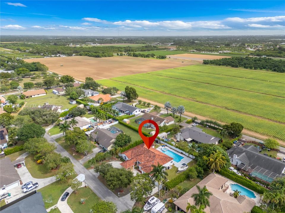 Aerial view of residential property featuring a clay tile roof, a private swimming pool, and a paved circular driveway
