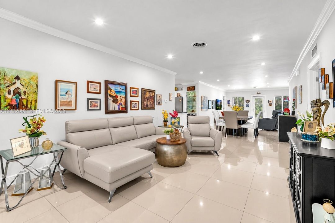 Open-concept floor plan featuring light-toned tile flooring, recessed lighting, and crown molding