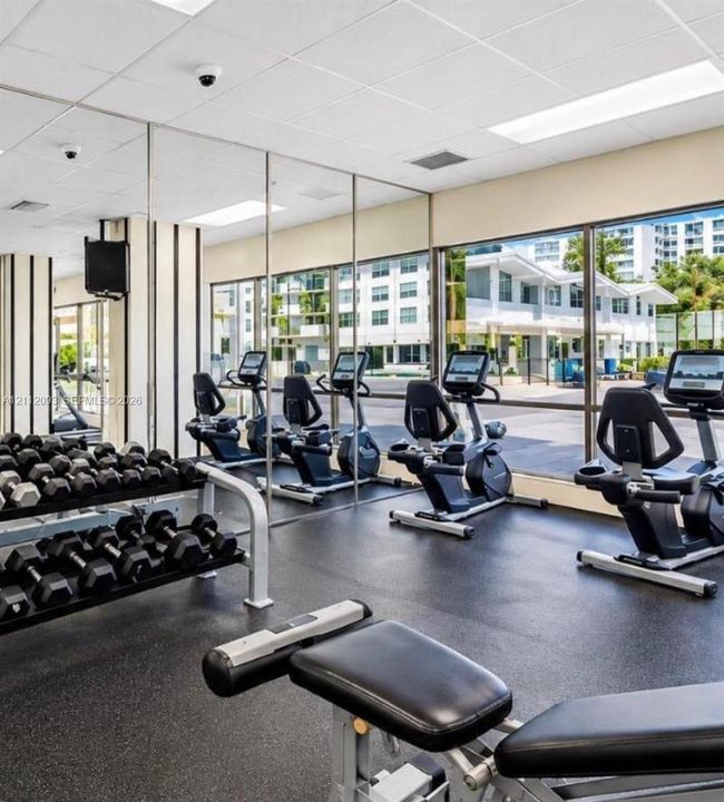 Fitness center featuring wall-to-wall mirrors, floor-to-ceiling windows, and impact-resistant flooring