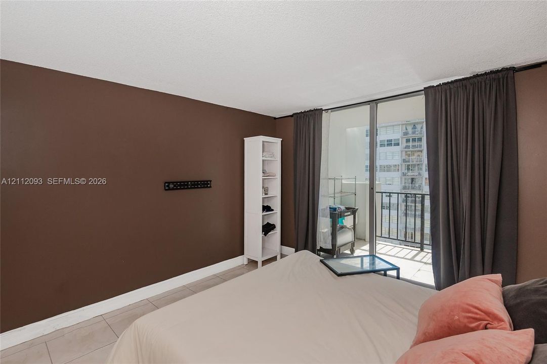 Large-format tile flooring and floor-to-ceiling glass sliding doors providing access to a private balcony with metal railing