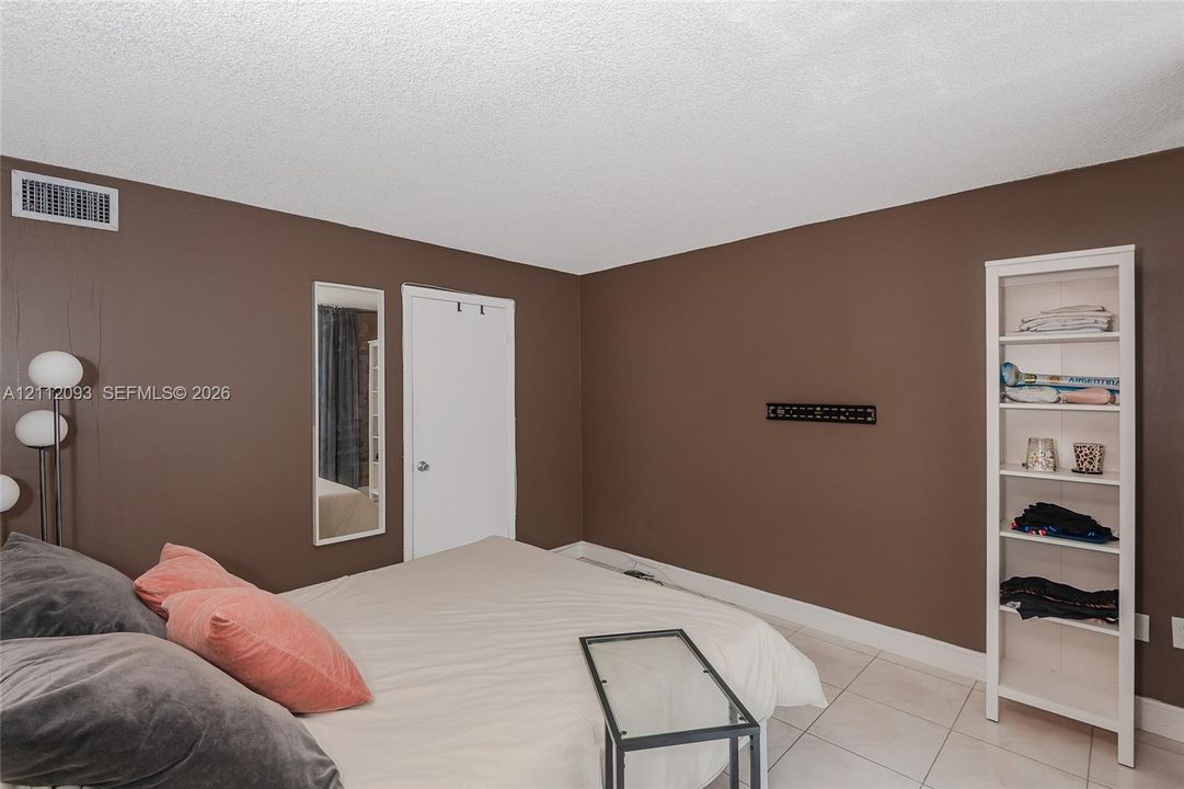 Room featuring tile flooring, built-in shelving, and a wall-mounted mirror