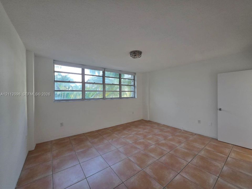 Interior space featuring large multi-pane horizontal windows, neutral tile flooring, a flush-mount ceiling light fixture, and a solid-core interior door