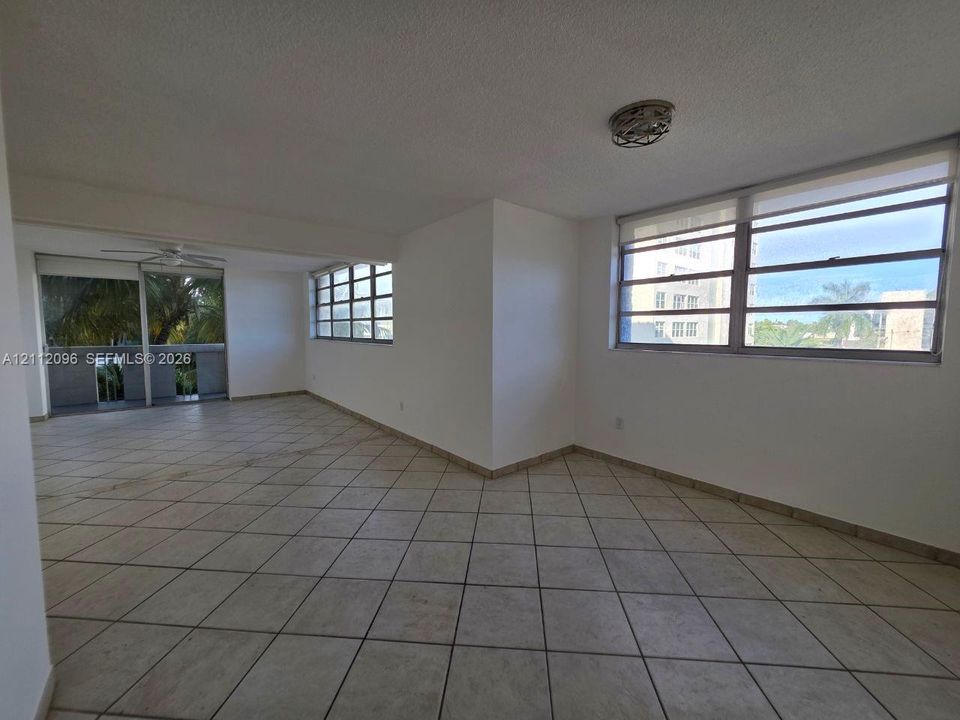 Neutral ceramic tile flooring, multiple expansive window bays, white wall finish, and an enclosed balcony area