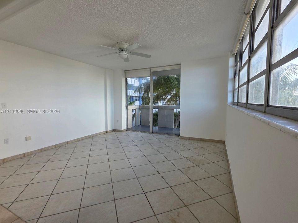 Interior space featuring large-format diagonal tile flooring, floor-to-ceiling windows, a white ceiling fan, and access to a private balcony