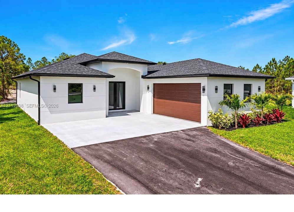Single-story residence featuring a smooth stucco exterior, asphalt shingle roof, two-car garage with wood-finish door, concrete driveway, and professional landscaping