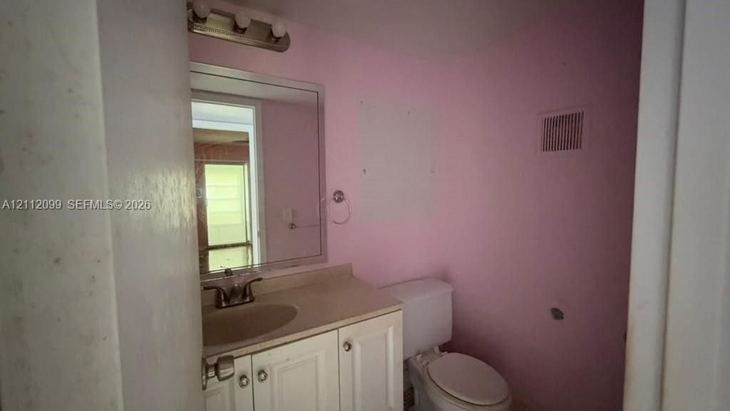 Bathroom featuring a white vanity cabinet with an integrated basin, a polished chrome faucet, a rectangular wall-mounted mirror, and a three-light vanity fixture