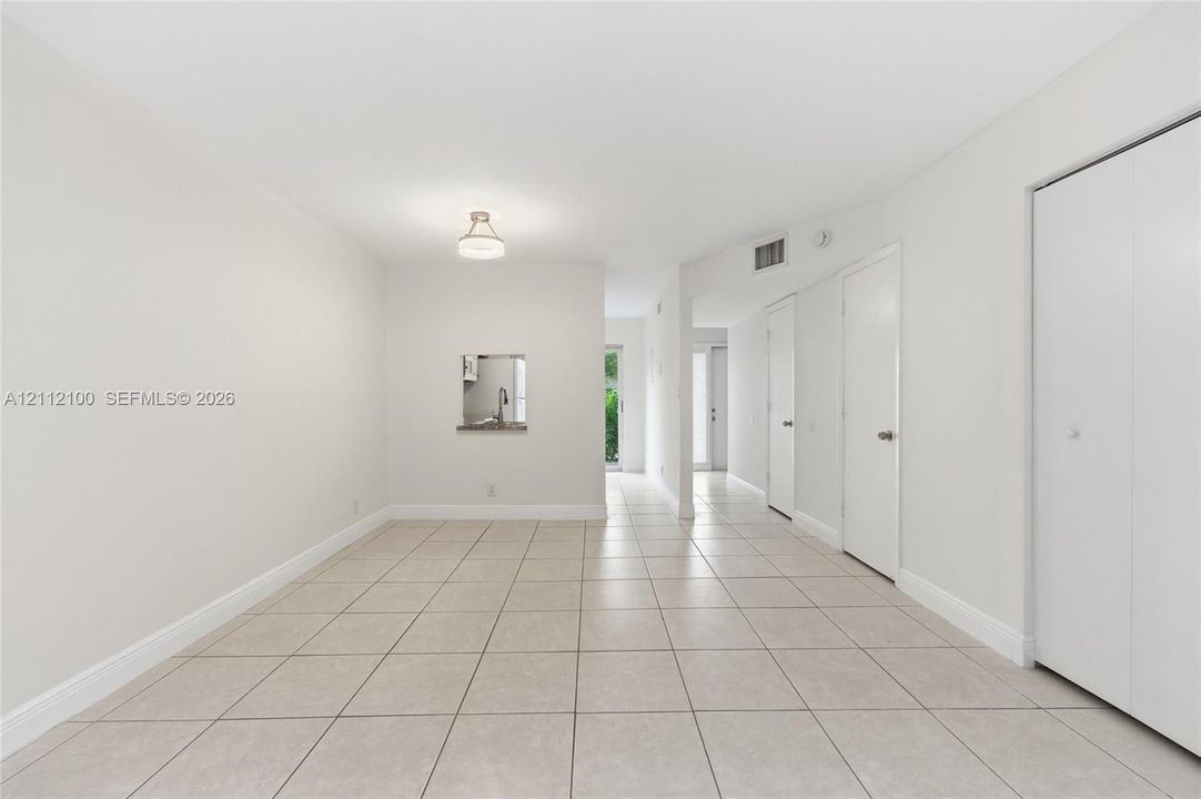 Neutral-toned tile flooring, recessed pass-through window, and minimalist flush-mount lighting