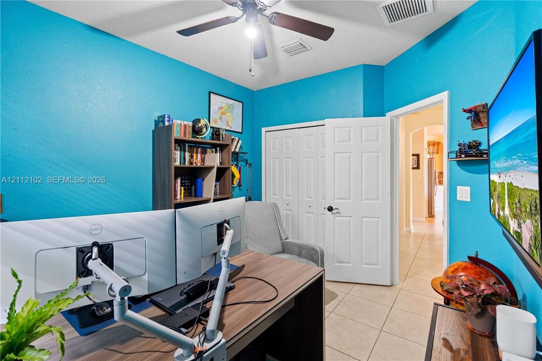 Room featuring tile flooring, a multi-blade ceiling fan with integrated light fixture, and a reach-in closet with six-panel bi-fold doors