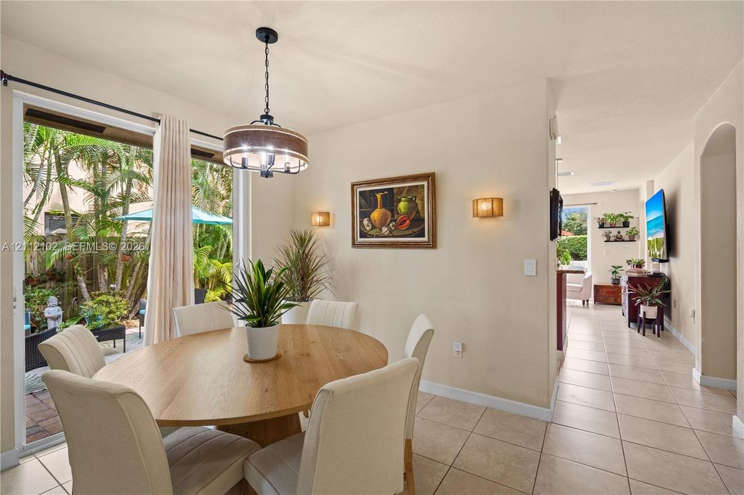 Ceramic tile flooring, sliding glass door with exterior access, drum-style pendant lighting, and dual wall-mounted sconces