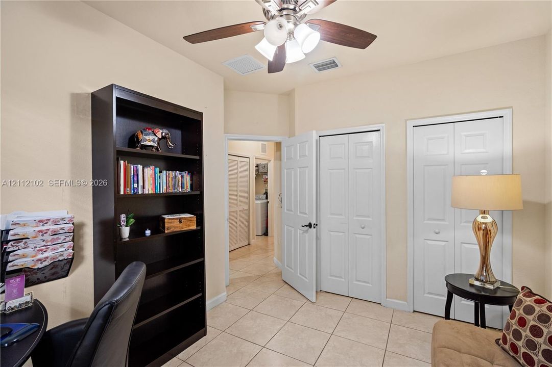 Ceramic tile flooring, two white bi-fold closet doors, and a ceiling fan with integrated lighting