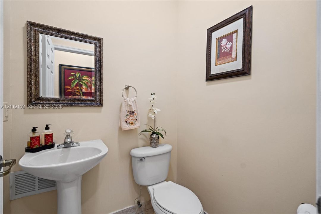Powder room featuring a pedestal sink with a single-handle faucet and a decorative wall-mounted mirror