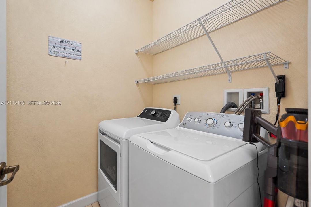 Laundry area featuring white wire wall-mounted shelving and recessed utility hookups