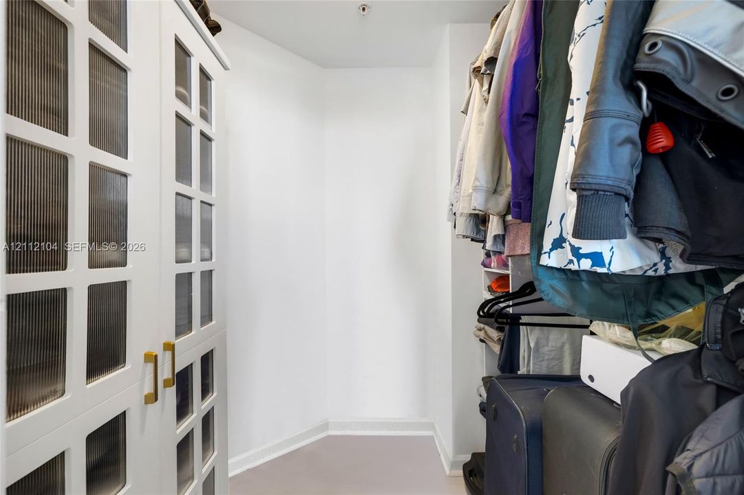 Built-in storage cabinetry featuring white frames, fluted glass cabinet doors, and metallic hardware