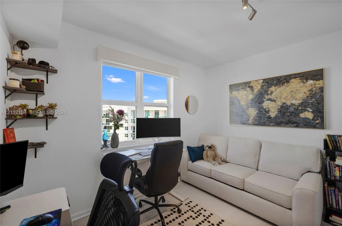 Room featuring neutral-toned walls, a large window with a roller shade, and four wall-mounted floating shelves