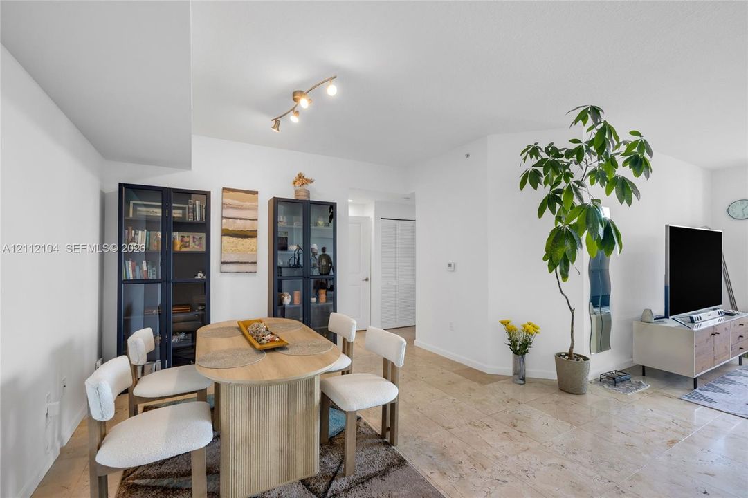 Open-concept interior featuring light-toned stone tile flooring, neutral wall finishes, and a modern multi-directional ceiling light fixture
