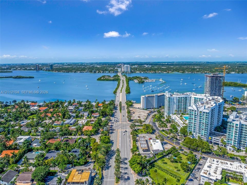 Aerial perspective featuring an expansive coastal landscape, deep-water bay, bridge infrastructure, and high-density residential developments