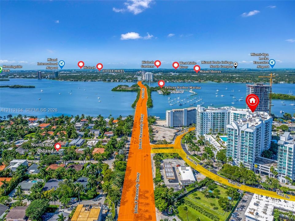 Aerial perspective of a high-rise residential building situated near the waterfront, featuring proximity to primary transportation arteries and coastal landmarks