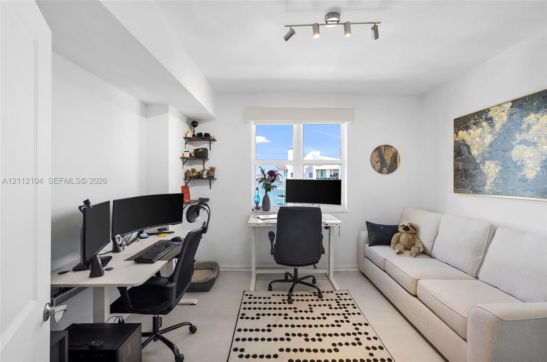Multi-purpose room featuring a multi-light directional ceiling fixture, window with natural lighting, and wall-mounted shelving