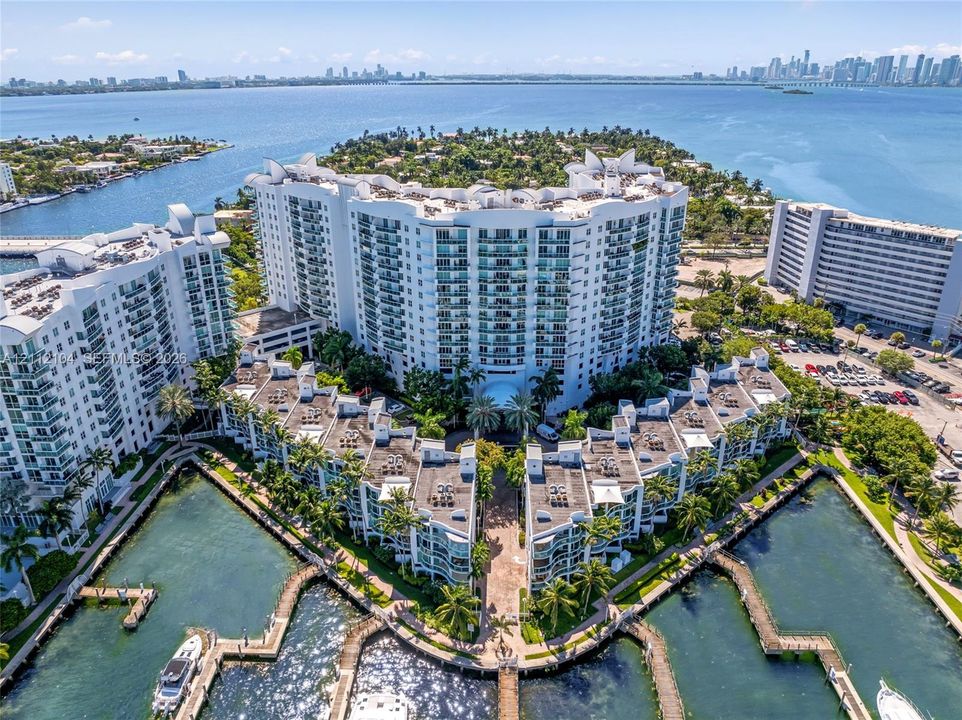 Waterfront high-rise complex featuring private boat slips, multi-level balconies, exterior stucco finish, and landscaped grounds